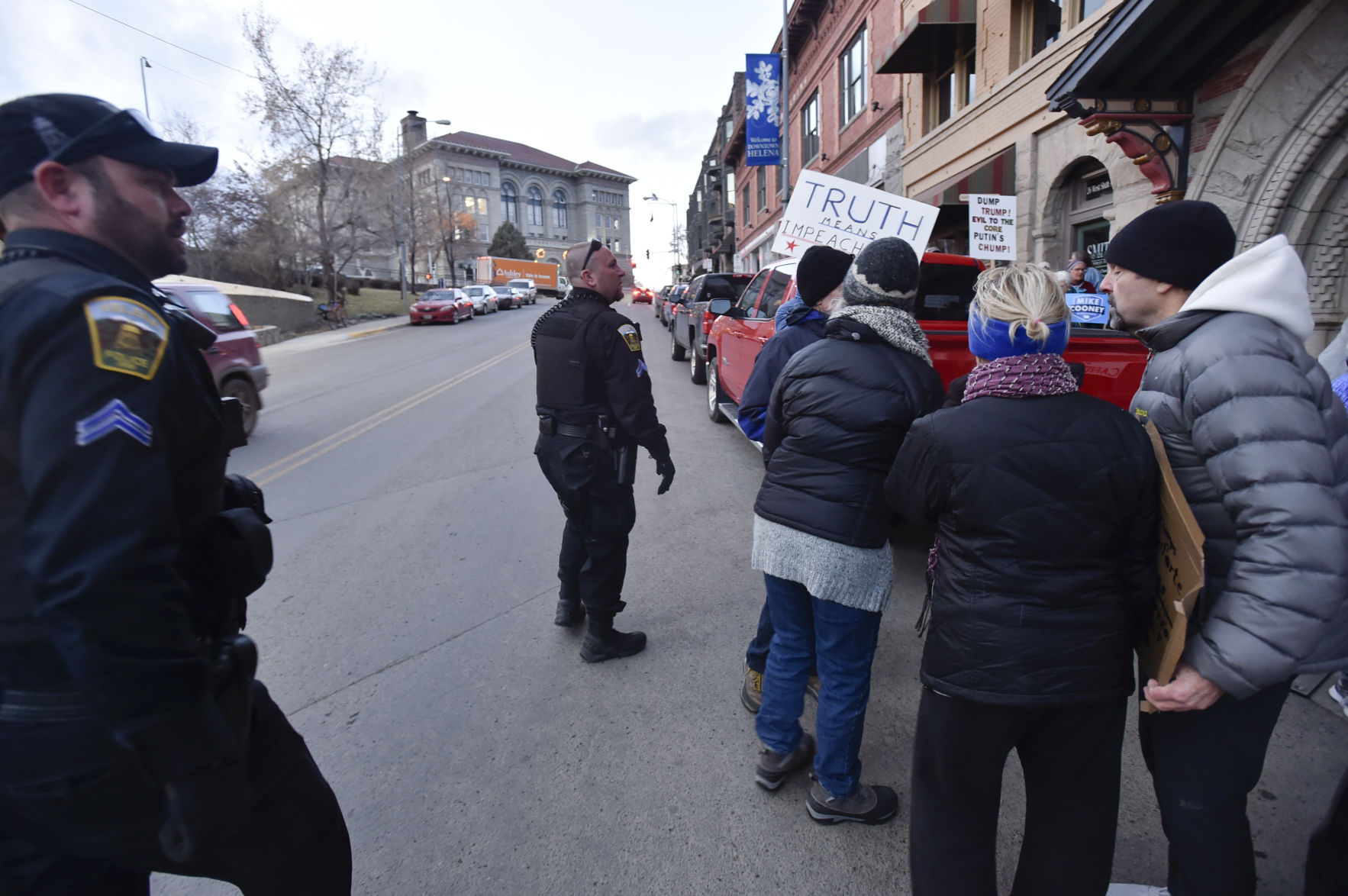 Helena police officers move protesters off the street Sunday evening outside the Montana Club.